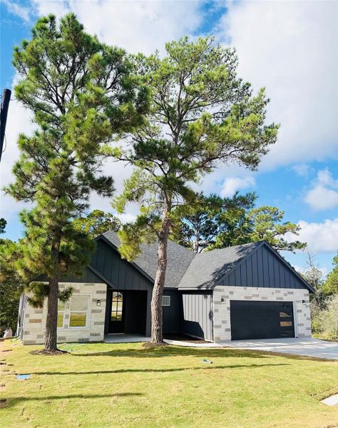 Modern farmhouse featuring board and batten siding, a front lawn, a garage, and roof with shingles
