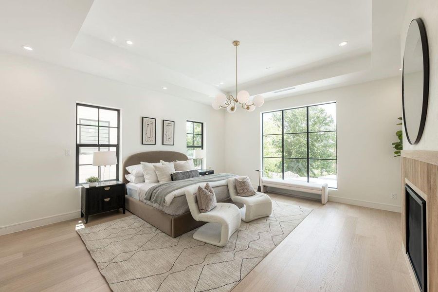 A serene primary suite where soft textures and layered neutrals create an atmosphere of effortless luxury. The tray ceiling and sculptural chandelier elevate the space, while oversized windows invite in natural light for tranquil mornings and peaceful evenings.