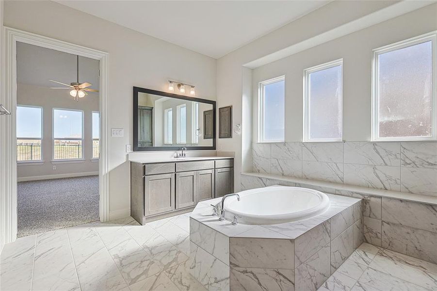 Full bathroom featuring vanity, light marble finish flooring, a bath, ceiling fan, and light colored carpet