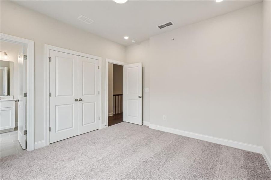 Unfurnished bedroom with carpet, connected bathroom, a closet, and recessed lighting
