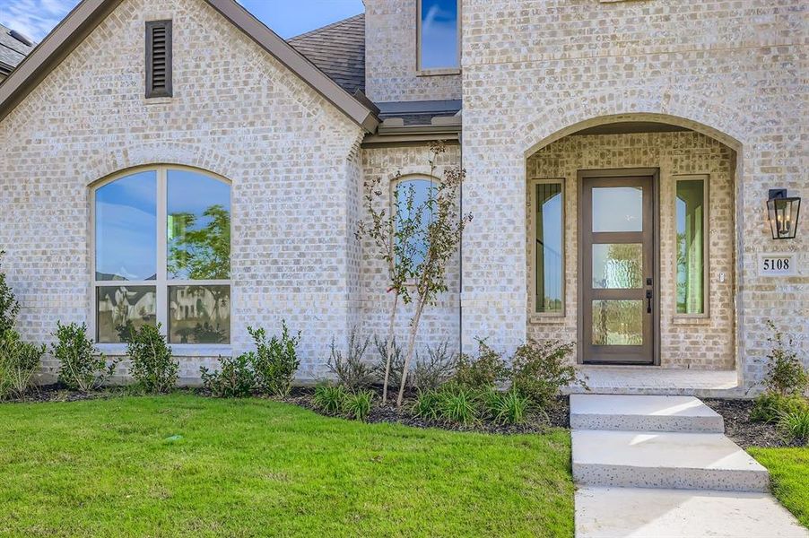 Entrance to property with brick siding, a yard, and roof with shingles Entrance to property with brick siding, a yard, and roof with shingles
