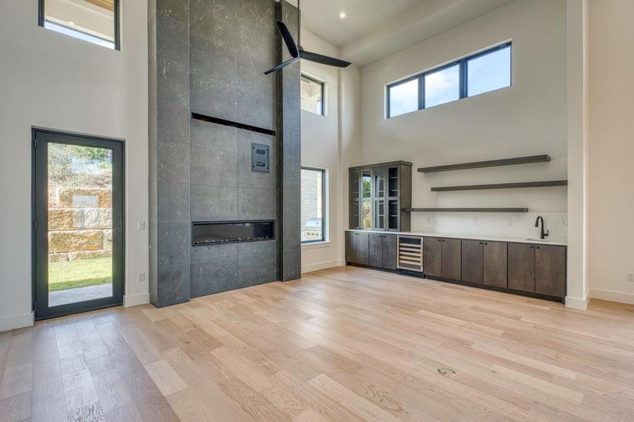 Hardwood floors and a towering stone fireplace define this double-height living room with built-in bar. Hardwood floors and a towering stone fireplace define this double-height living room with built-in bar.