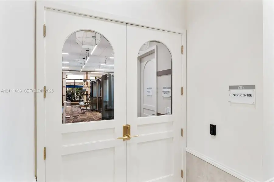Double doors featuring arched glass panels, brass hardware, and electronic keyless entry