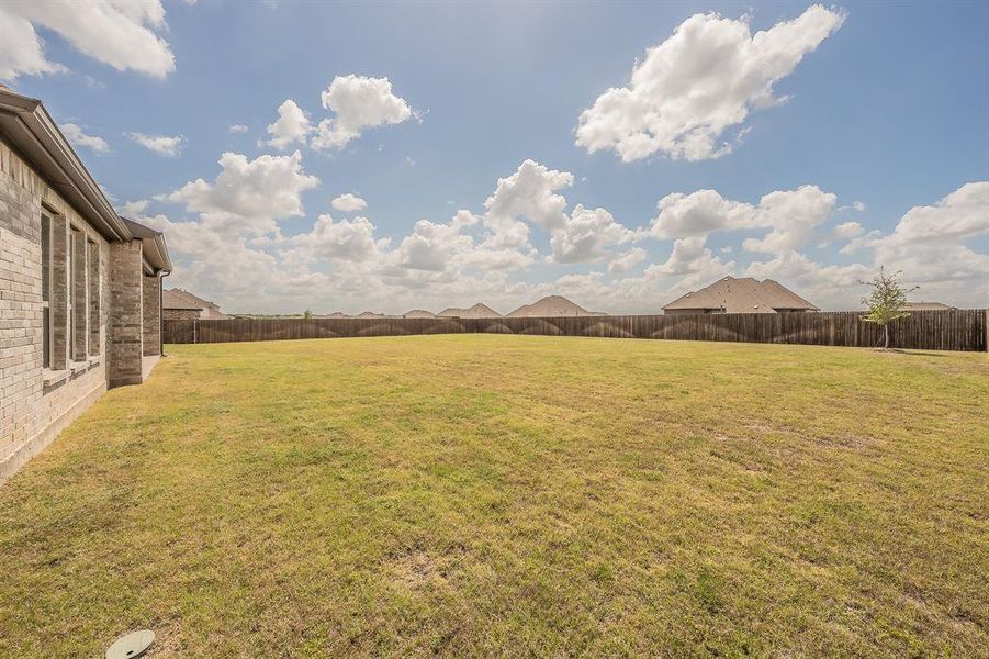 The property features an extensive backyard with a large lawn and a wood fence