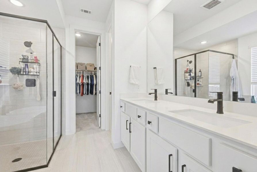 Full bath with a stall shower, double vanity, a spacious closet, and recessed lighting