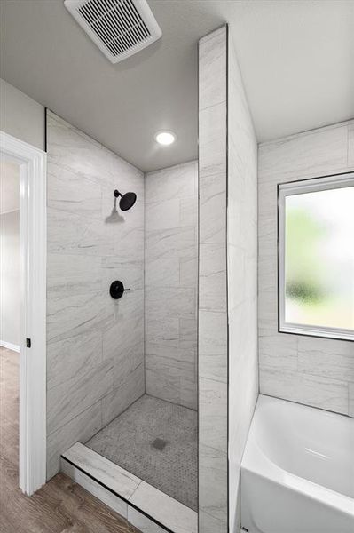 Walk-in shower featuring large format tile surrounds, matte black fixtures, and a hexagon tile pan