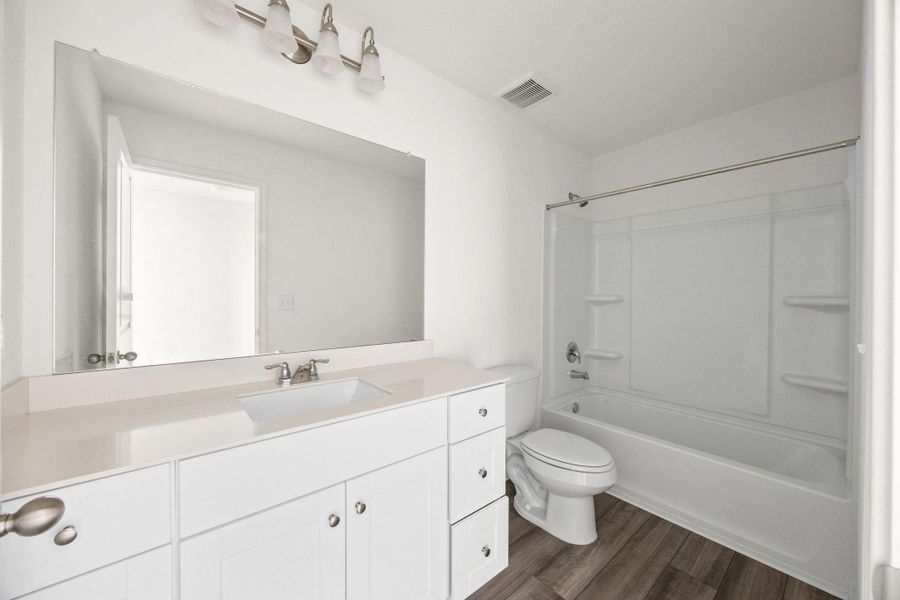 Bathroom with vanity, dark wood-style floors, and shower / tub combination
