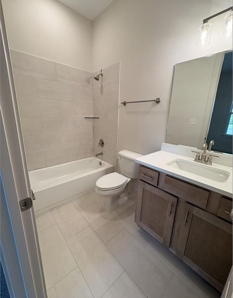 Bathroom featuring a single vanity with a white countertop, wood-finish cabinetry, and a chrome faucet