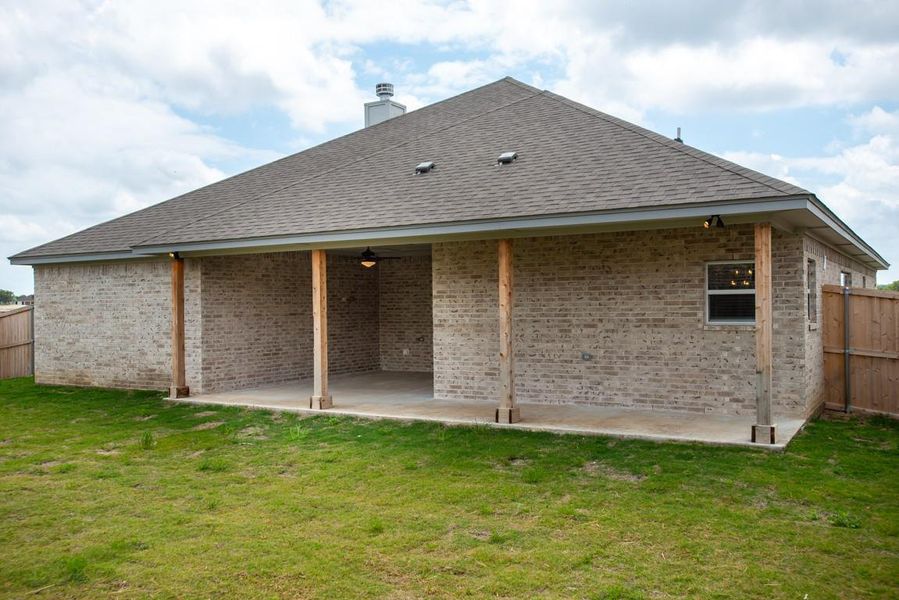 Back of house with a patio area, brick siding, a chimney, a ceiling fan, and a shingled roof Back of house with a patio area, brick siding, a chimney, a ceiling fan, and a shingled roof