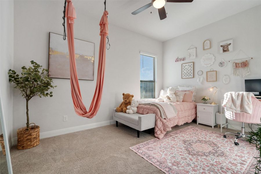 A well-lit bedroom features plush carpeting, a wide window with blinds, and a functional ceiling fan. A well-lit bedroom features plush carpeting, a wide window with blinds, and a functional ceiling fan.