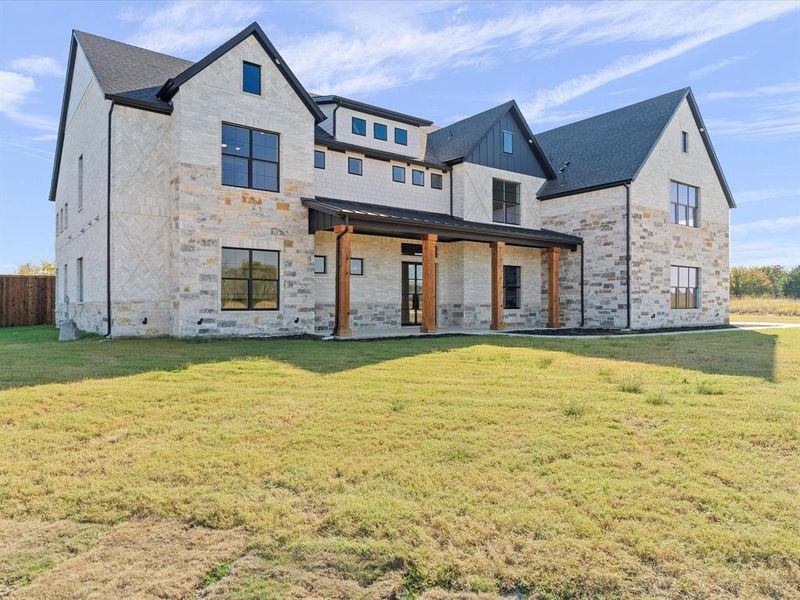 Rear view of house with a yard, stone siding, a porch, and a standing seam roof