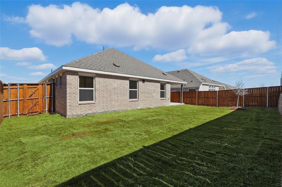 Rear view of house with a yard, a fenced backyard, and brick siding