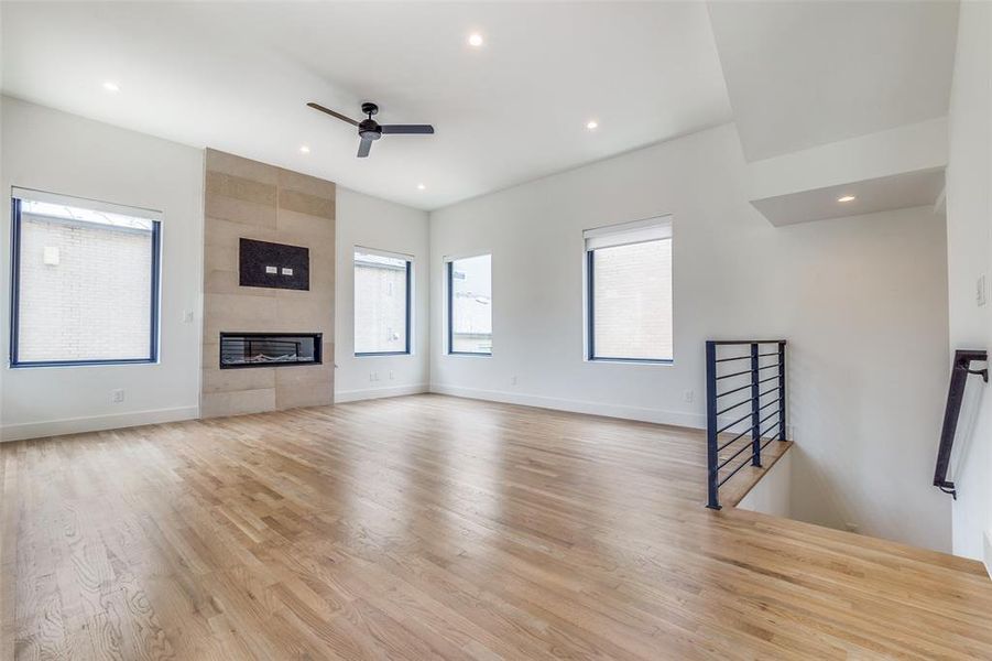 The living area on the second level boasts an abundance of natural light and is anchored by a sleek gas fireplace surrounded by modern stone.