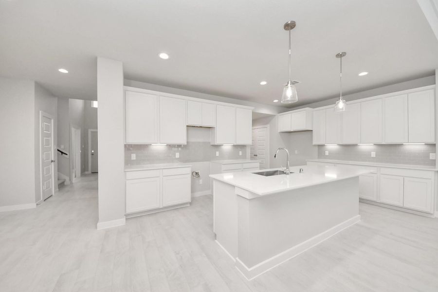 The kitchen is a culinary haven, featuring granite countertops, a tile backsplash, stainless steel appliances, 42” upper cabinets, and undercabinet lighting. Sample photo of completed home with similar floor plan. Actual colors and selections may vary. The kitchen is a culinary haven, featuring granite countertops, a tile backsplash, stainless steel appliances, 42” upper cabinets, and undercabinet lighting. Sample photo of completed home with similar floor plan. Actual colors and selections may vary.