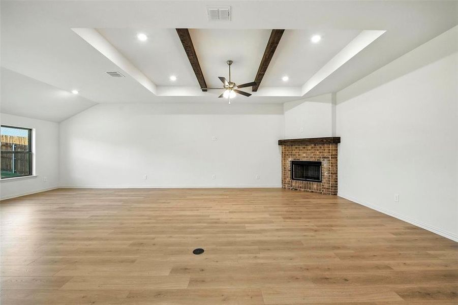 Unfurnished living room with a ceiling fan, light wood-style flooring, a fireplace, recessed lighting, and beam ceiling