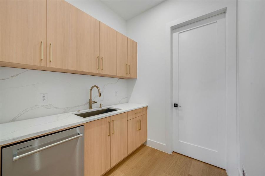 Kitchen featuring light brown cabinets, modern cabinets, dishwasher, light stone countertops, and tasteful backsplash Kitchen featuring light brown cabinets, modern cabinets, dishwasher, light stone countertops, and tasteful backsplash