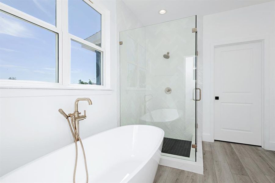 Bathroom with a shower stall, a freestanding tub, wood finished floors, and recessed lighting