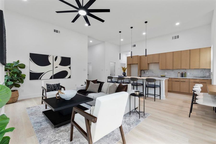 Living room with recessed lighting, a high ceiling, light wood-style flooring, and a ceiling fan