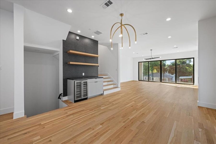 Dining room featuring light wood finished floors, recessed lighting, wine cooler, and a chandelier Dining room featuring light wood finished floors, recessed lighting, wine cooler, and a chandelier