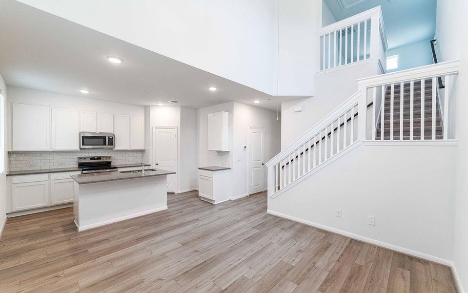 Kitchen with white cabinets, stainless steel appliances, an island with sink, light wood-type flooring, and recessed lighting