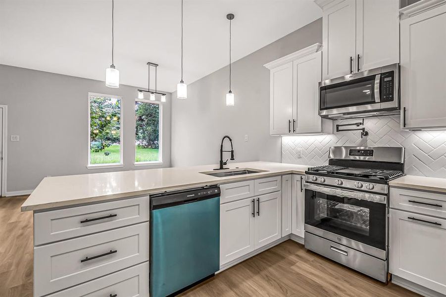 Spacious kitchen with stainless steel appliances, quartz countertops, pot filler at the stove and under cabinet lighting.