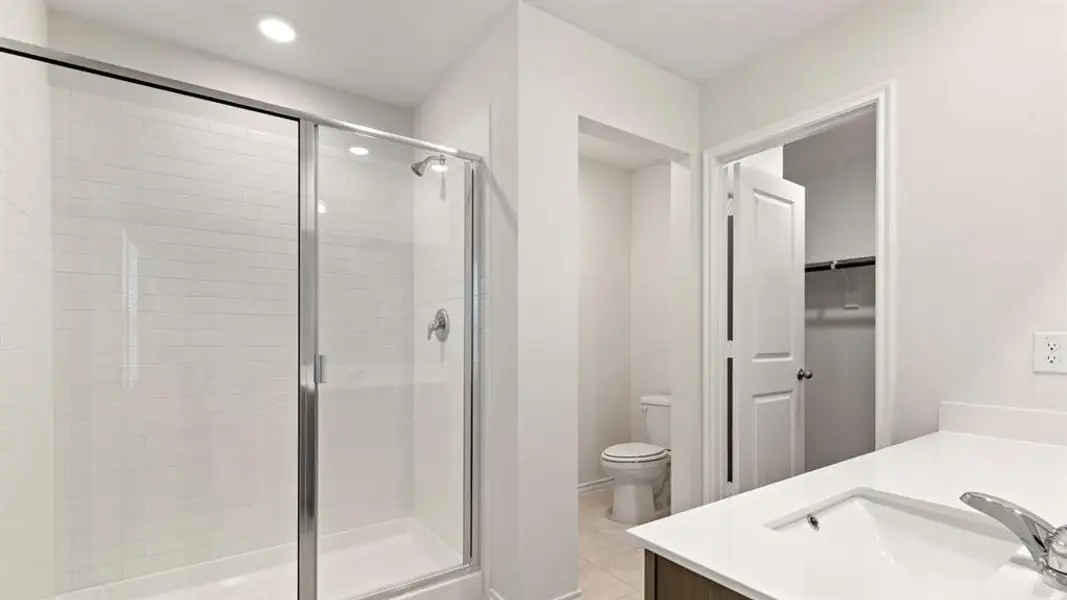 Contemporary bathroom featuring a glass-enclosed shower with subway tile surround, single vanity with integrated sink and chrome faucet, and a separate water closet