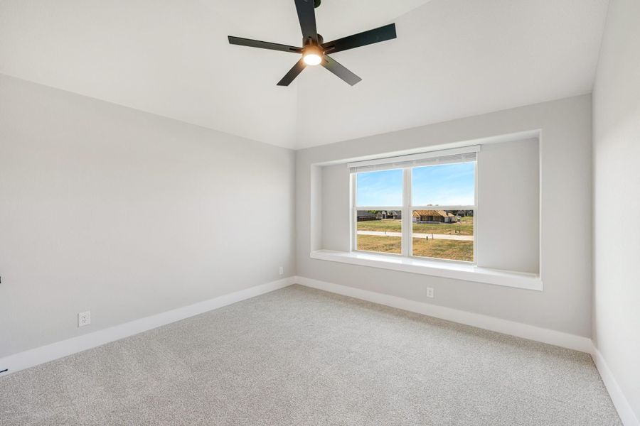 Empty bedroom with gray carpet, ceiling fan, and large window with outdoor view Empty bedroom with gray carpet, ceiling fan, and large window with outdoor view