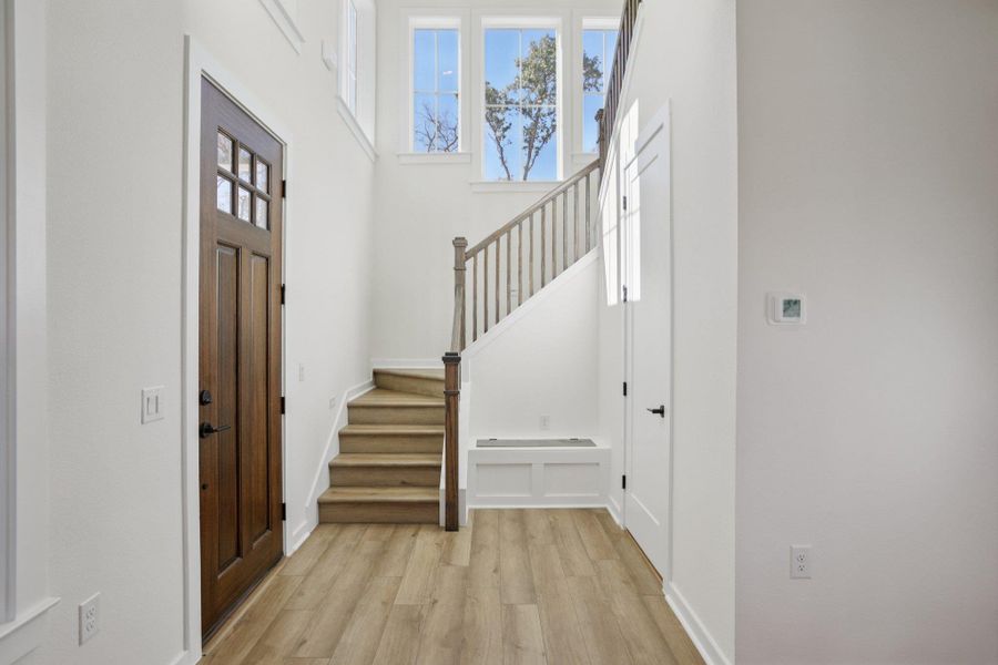 Foyer featuring stairs, a high ceiling, and light wood-style floors
