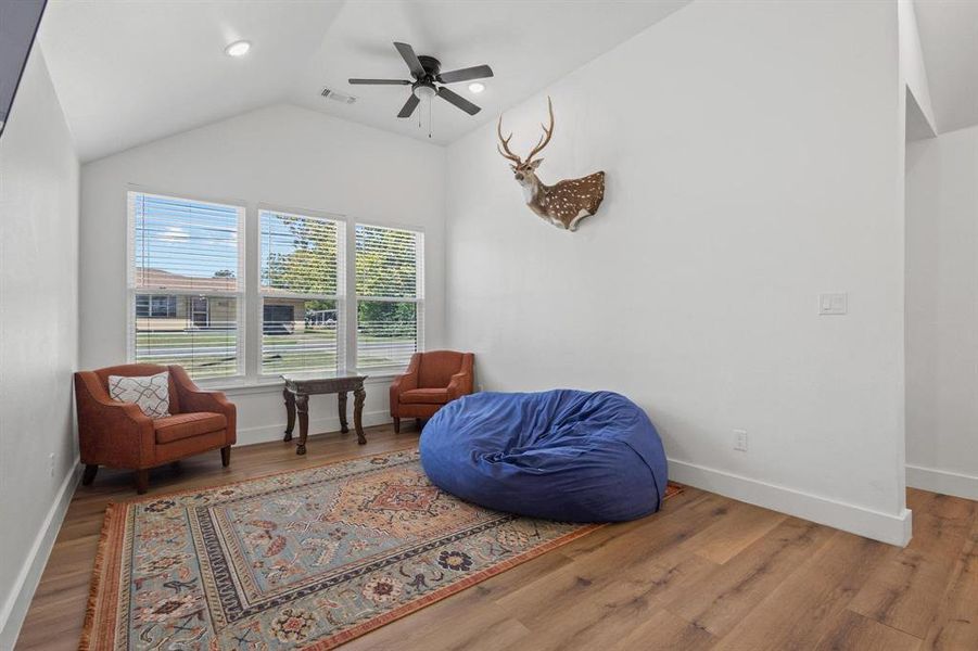 Living area featuring wood finished floors, vaulted ceiling, a ceiling fan, and recessed lighting