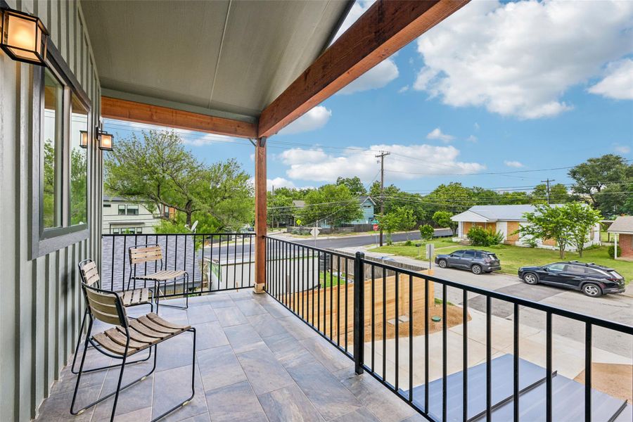 An inviting covered dbalcony with tiled flooring offers serene neighborhood views.