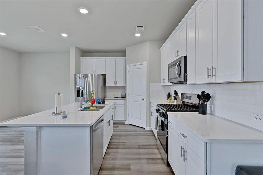 The kitchen features white cabinetry, white countertops, and stainless steel appliances