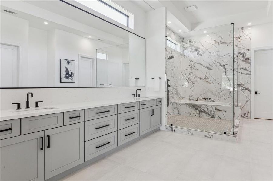 This primary bathroom features a spacious double vanity with sleek cabinetry, a large frameless glass shower, and elegant marble detailing for a modern and luxurious feel.