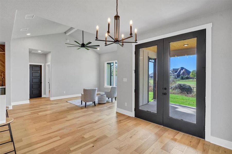 Foyer entrance featuring a chandelier, light wood-style floors, french doors, and a ceiling fan Foyer entrance featuring a chandelier, light wood-style floors, french doors, and a ceiling fan