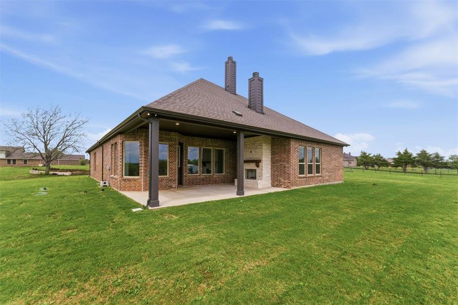 Rear view of house featuring brick siding, a chimney, a patio area, and roof with shingles