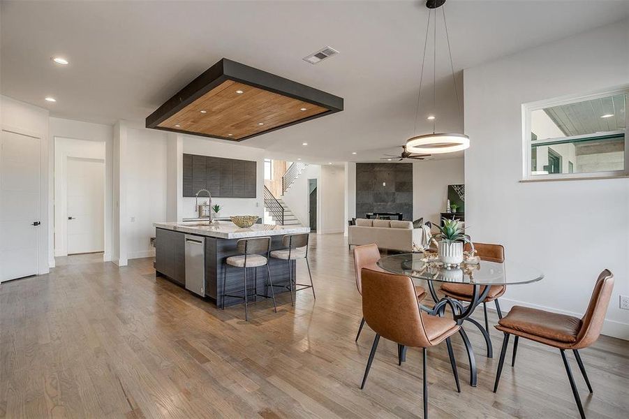 Dining room with visible vents, stairs, light wood-type flooring, a fireplace, and recessed lighting