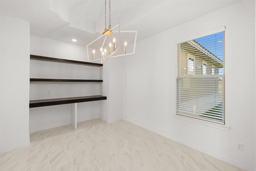 Unfurnished dining area featuring suspended lighting and baseboards