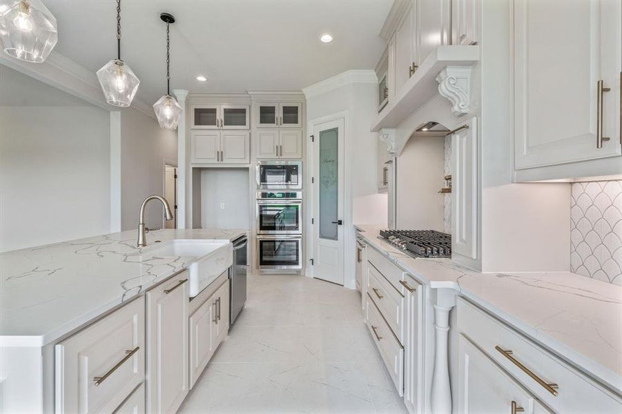 Kitchen featuring a sink, stainless steel appliances, hanging light fixtures, light marble finish floors, and recessed lighting
