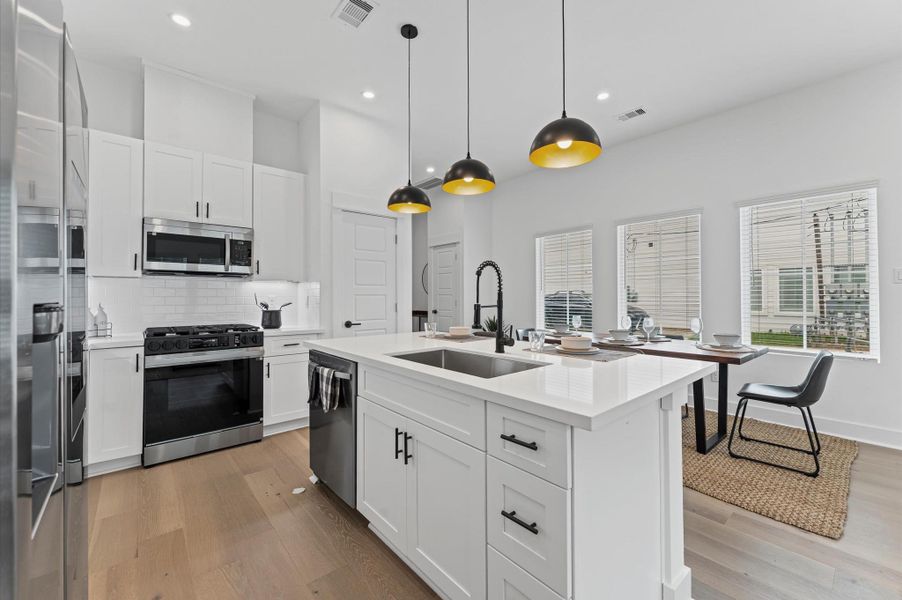 This centrally positioned kitchen island serves as a stylish anchor within the open-concept layout, offering clear sightlines to the dining area, living space, and the front yard. Its placement encourages seamless interaction, whether prepping meals or entertaining guests, while natural light pours in through the nearby windows. The island’s sleek design and functional surface make it a hub of activity, framed by elegant finishes tying together comfort and sophistication.