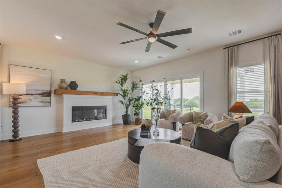 Another view of the living area highlights the seamless connection to the outdoor patio through large sliding doors. The fireplace adds warmth and character, while tall windows enhance the bright, airy feel of the space. Thoughtful design elements and an open layout make this area perfect for both everyday living and hosting guests. The picture shown is from the model home with the same floor plan, Rev floor plan.