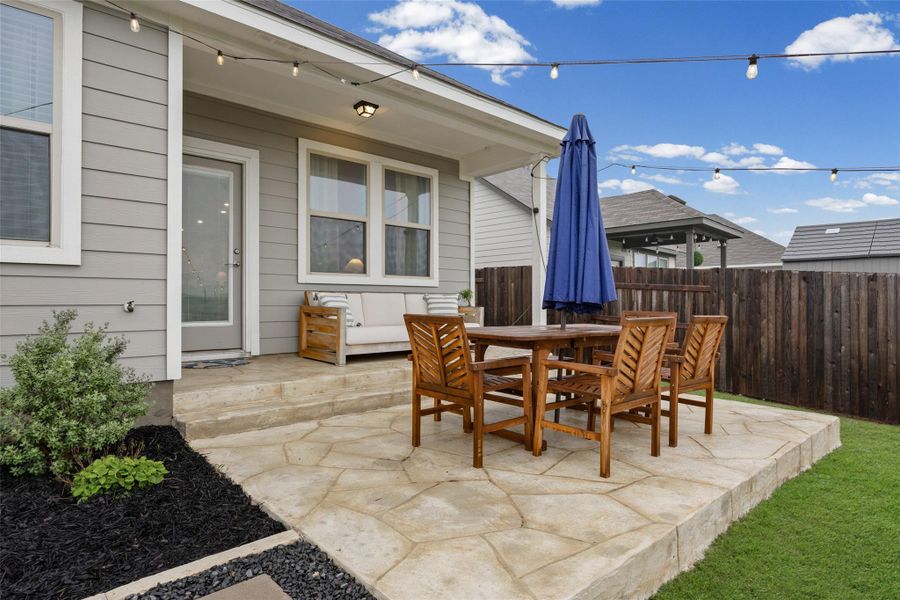 Expansive rear patio featuring flagstone-style concrete and a raised concrete border
