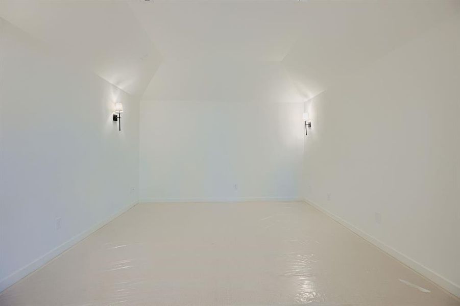 Additional living space featuring vaulted ceiling and finished concrete flooring Additional living space featuring vaulted ceiling and finished concrete flooring