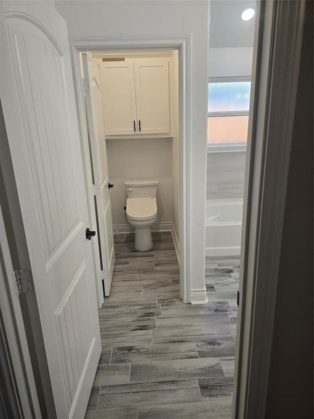 Bathroom with hardwood / wood-style floors, toilet, and a tub