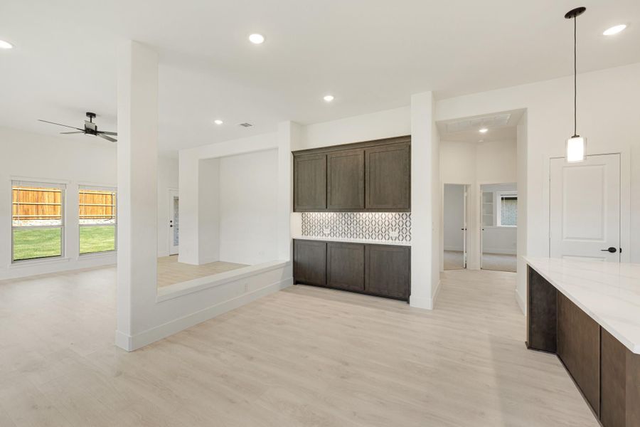 Open-concept living and kitchen area with dark wood cabinets, light wood floors, and ceiling fan