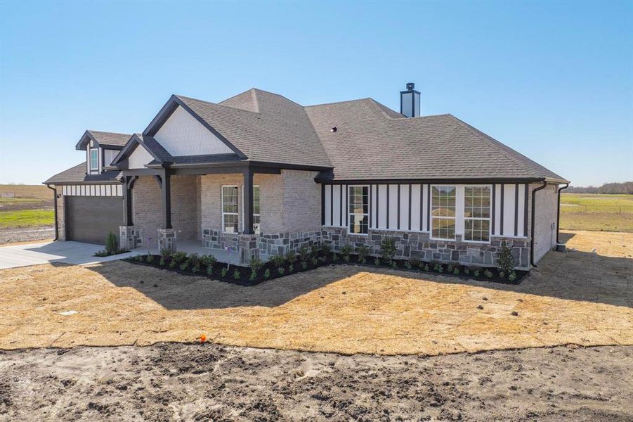 View of front of house with a porch, an attached garage, driveway, and roof with shingles