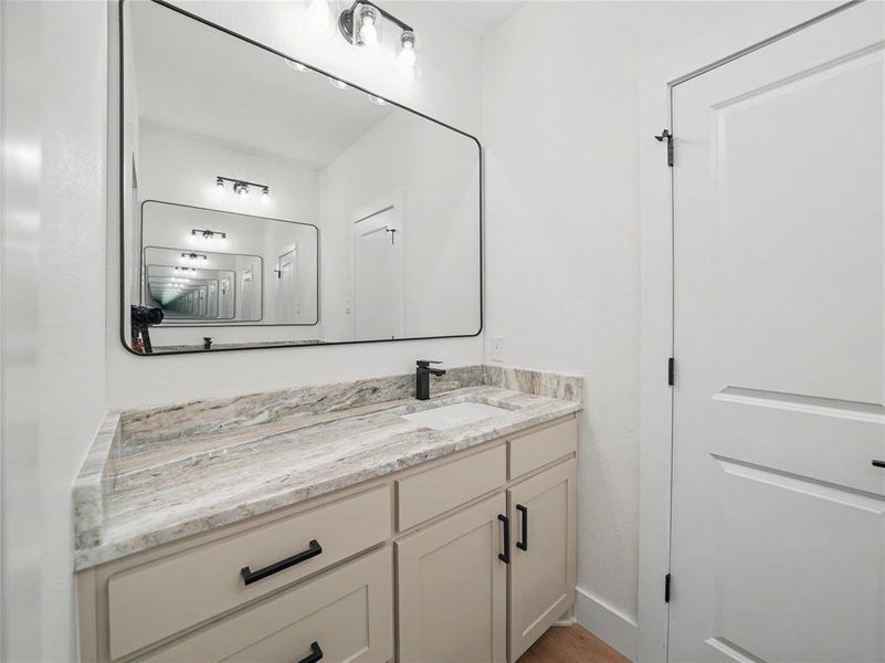 Bathroom vanity featuring an integrated sink, stone-finish countertop, and matte black fixtures Bathroom vanity featuring an integrated sink, stone-finish countertop, and matte black fixtures