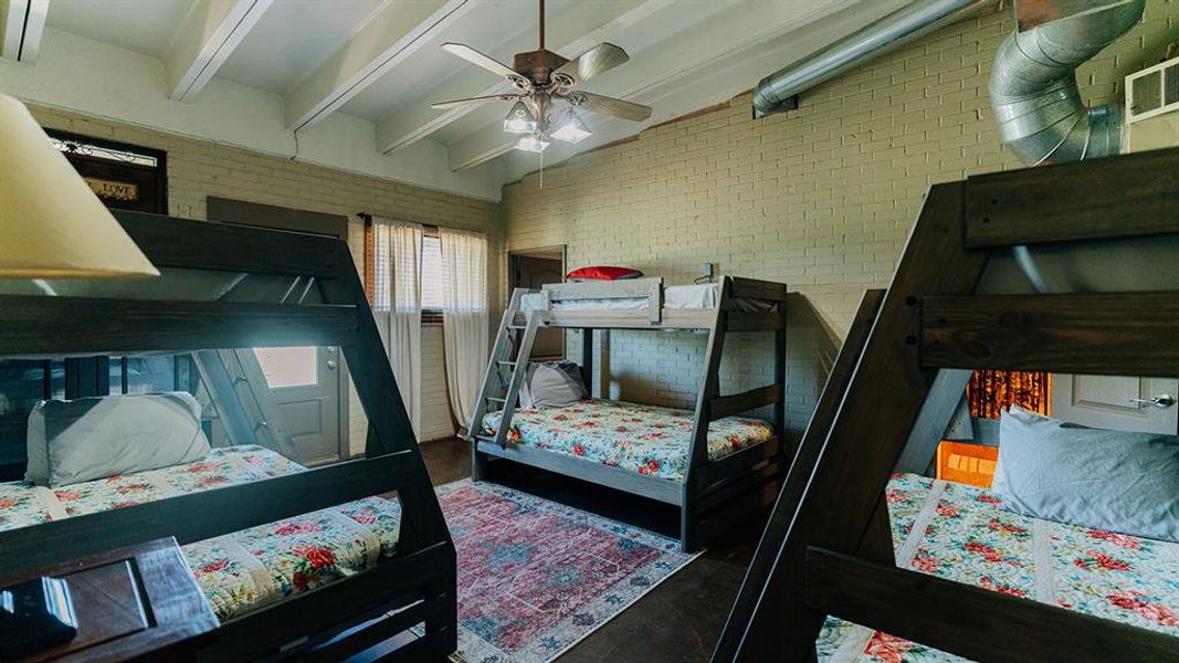 Bedroom featuring brick wall, beam ceiling, and a ceiling fan