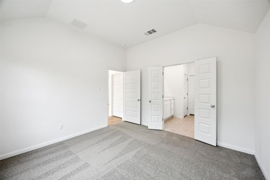 Unfurnished bedroom with light carpet, vaulted ceiling, and ensuite bath Unfurnished bedroom with light carpet, vaulted ceiling, and ensuite bath