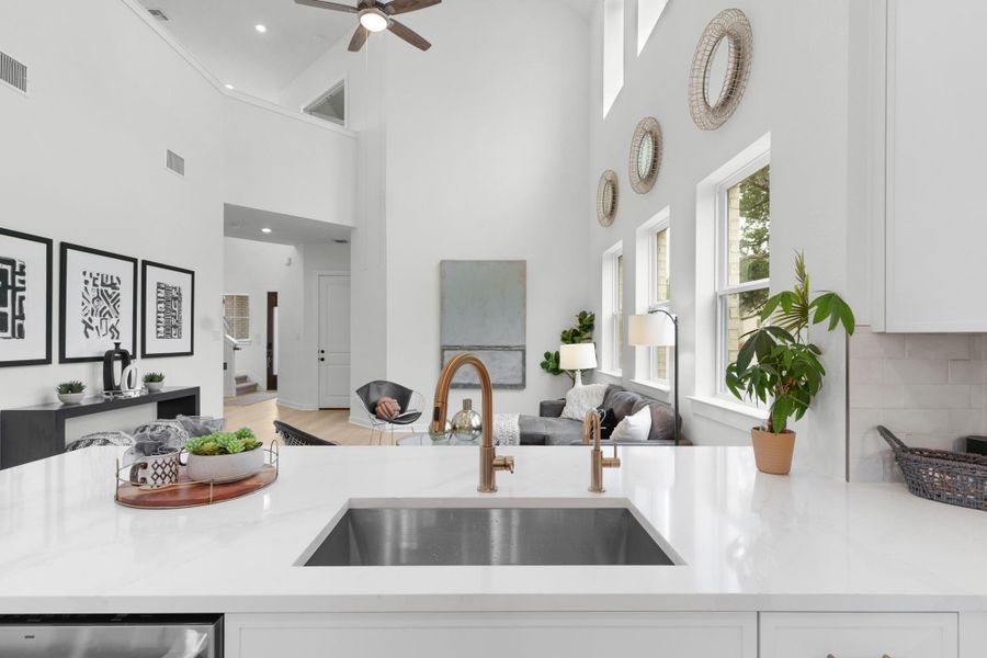 Kitchen featuring a sink, a high ceiling, white cabinetry, a ceiling fan, and open floor plan