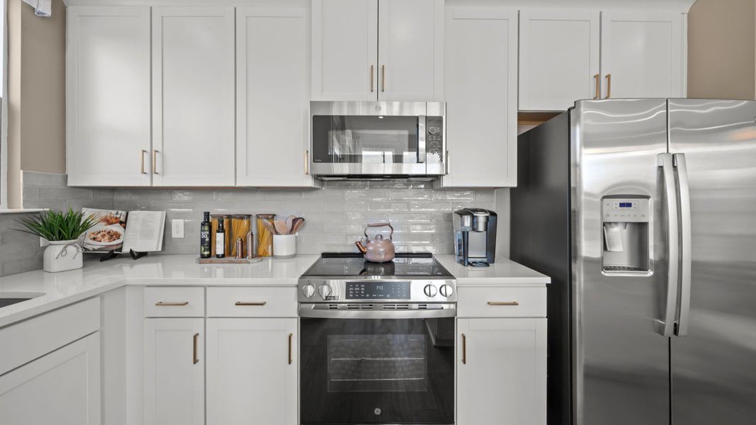 The Rochester Plan by DRB homes kitchen with white cabinets, silver appliances and gold features in Charlotte, NC.