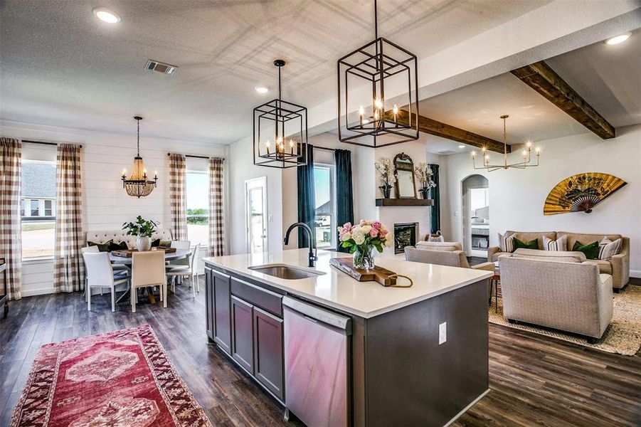 Kitchen with a center island with sink, stainless steel dishwasher, sink, and hanging light fixtures